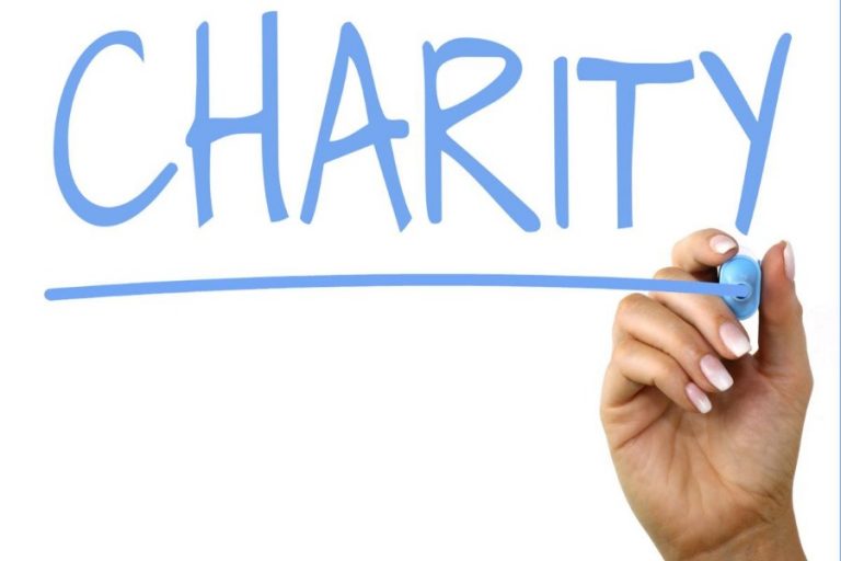 A hand with a blue marker writes "CHARITY" in large letters on a whiteboard, highlighting the importance of supporting the shrinking charities sector.