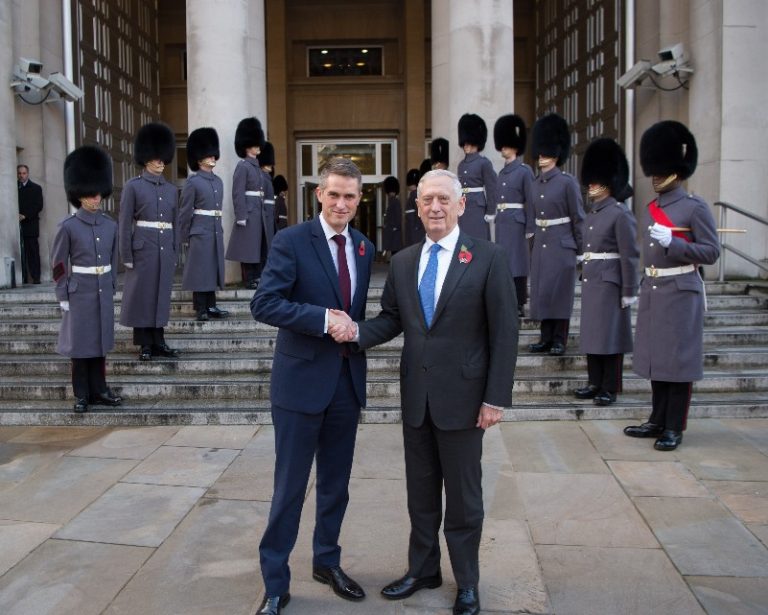 Two men in suits, including Williamson, shake hands outside a building, with guards in ceremonial uniforms standing in formation behind them. This marks a significant step in the Defence Prosperity Programme.
