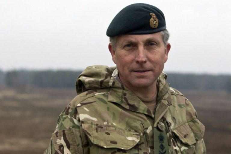A person in military uniform stands outdoors, wearing a camouflage jacket and a green beret, embodying the readiness and discipline characteristic of the Defence Staff.