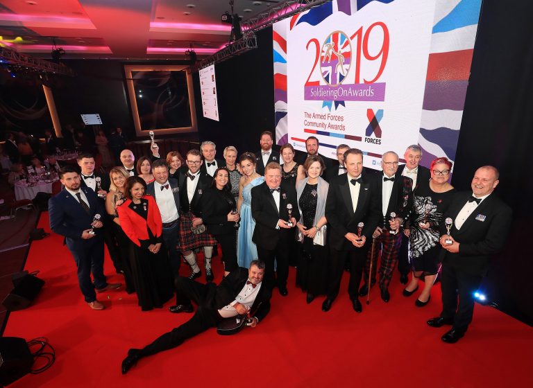 A shining example of success, a group of people in formal attire pose with awards on the red carpet at the event, inspiring us all with their achievements.