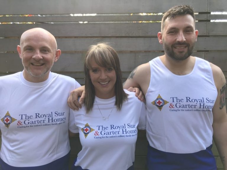 Three people in matching Royal Star & Garter Homes shirts stand with their arms around each other, smiling at the camera like marathon rookies conquering their first big race.