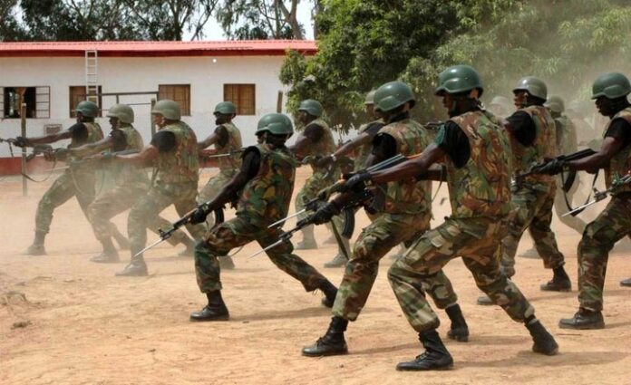 Soldiers in camouflage uniforms and helmets practice a coordinated drill with rifles in an outdoor setting, as part of the effort where the UK backs Nigeria's fight against extremism.