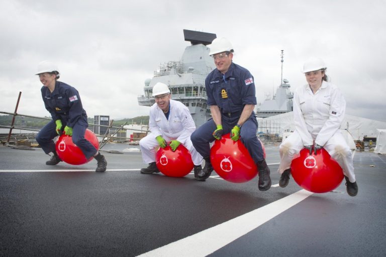 Four veterans in uniforms and helmets bounce back on red space hoppers on a ship's deck, with a large ship structure towering in the background.