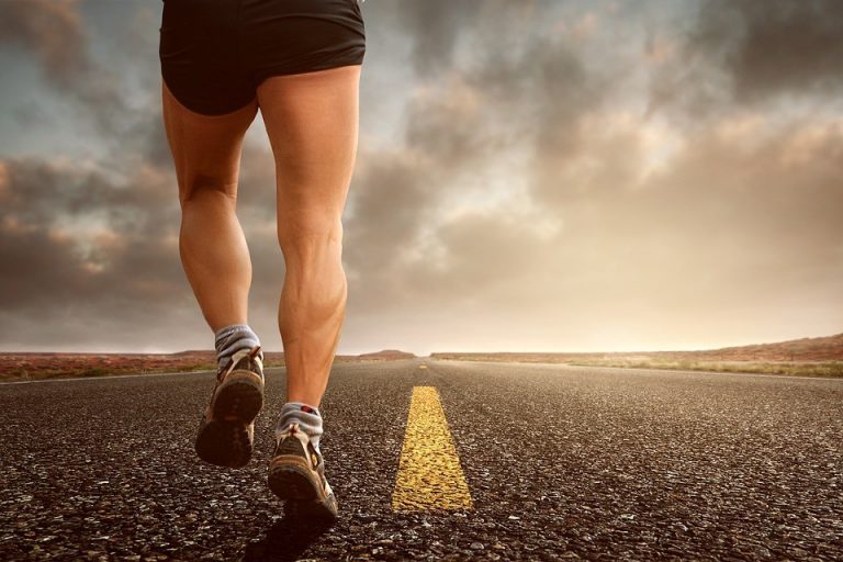 A person, embodying a healthy mind and body, runs along an open road as the sunset paints dramatic clouds across the sky.