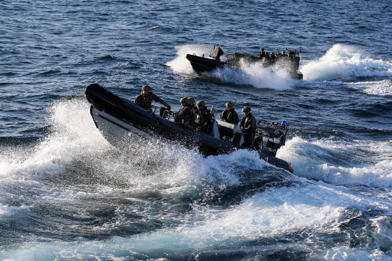 Two rigid inflatable boats swoop through choppy ocean waters, with marines onboard navigating the splashes and waves.