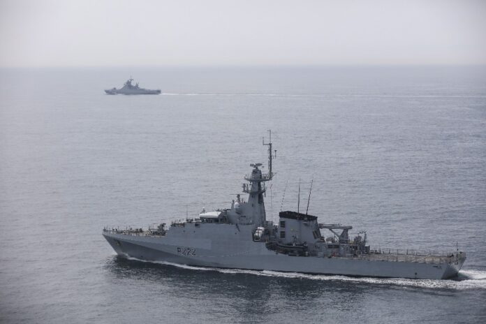 Two naval warships on the calm sea, one in close view with hull number P222, the other distant and slightly obscured by misty shadows.