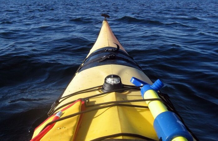 A yellow kayak loaded with gear glides through the vast expanse of the English Channel, as seen from the paddler's perspective under clear skies.