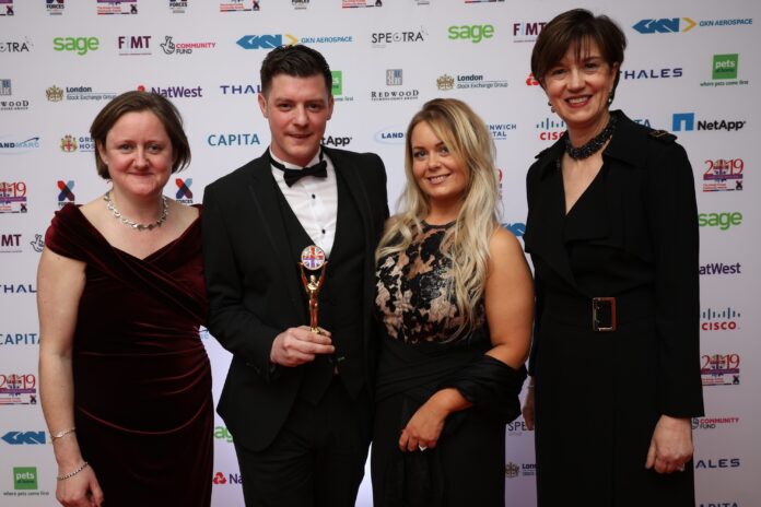 Four people in formal attire pose for a photo at an event, where someone proudly holds a trophy, embodying the spirit of recognition and inspiring others around them.