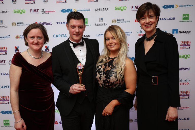 Four people in formal attire pose for a photo at an event, where someone proudly holds a trophy, embodying the spirit of recognition and inspiring others around them.