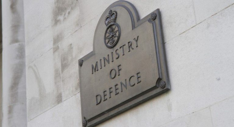 A gold-etched metal plaque on a stone wall reads "Ministry of Defence" with an emblem above, symbolizing the prestigious role it plays among employers.