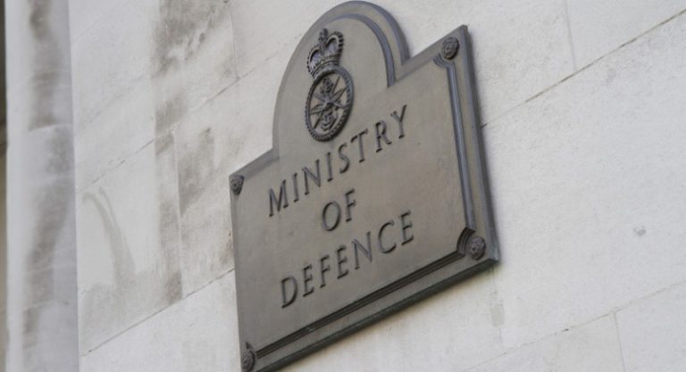 A plaque on a wall reads "Ministry of Defence," with an emblem above the text, symbolizing the strategic investment in Omani Port initiatives.