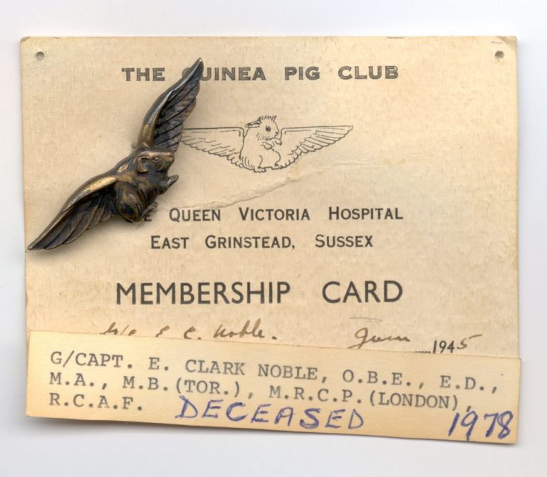 Vintage Guinea Pig Club membership card with a bronze bird pin. The card belonged to G/Capt. E. Clark Noble, noted "Deceased" in 1978 and issued by Queen Victoria Hospital in 1945, a key site for conflict wound research, now supported by the Scar Free Foundation.