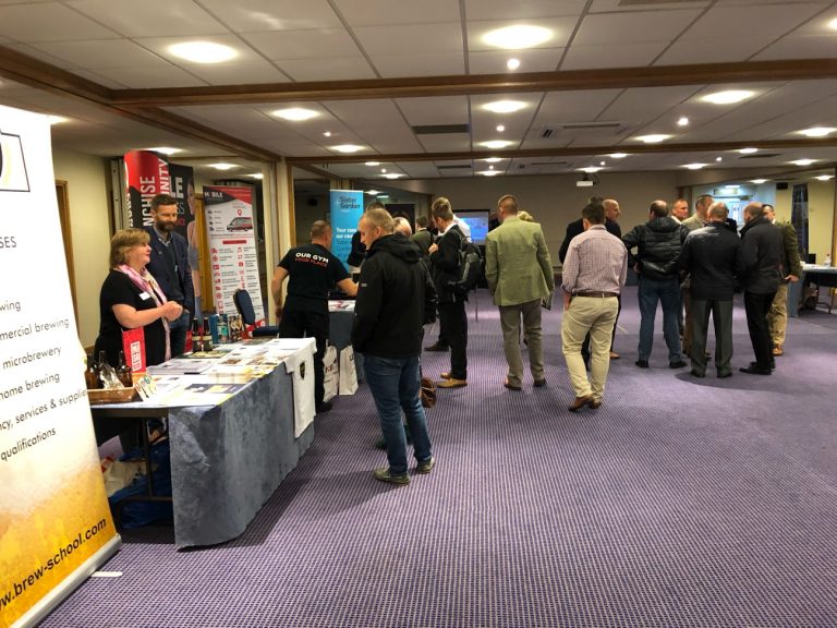 Visitors at the Resettlement Expo in Nottingham engage with various booths at the indoor business expo, exploring informational displays and promotional materials tailored for the Armed Forces community.