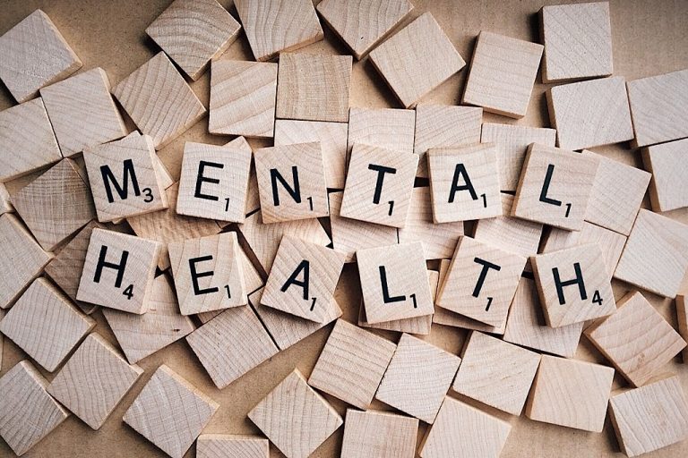 Scrabble tiles elegantly spell "Mental Health" amidst a scattered sea of blank tiles, subtly promoting awareness.