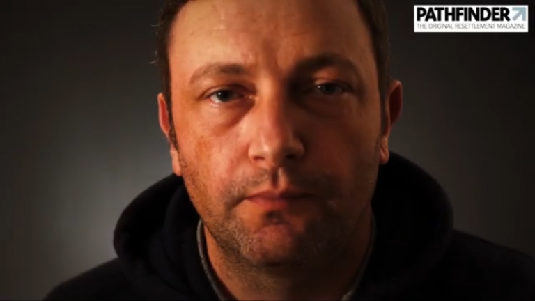 A person with short hair is wearing a dark hoodie, facing forward against a plain background. There's a "Pathfinder" magazine logo in the top right corner, reminiscent of Tommy Atkins’ steadfast spirit.