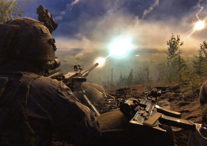 A Pathfinder soldier wearing tactical gear fires a machine gun at night, muzzle flash and smoke visible, surrounded by dense vegetation.