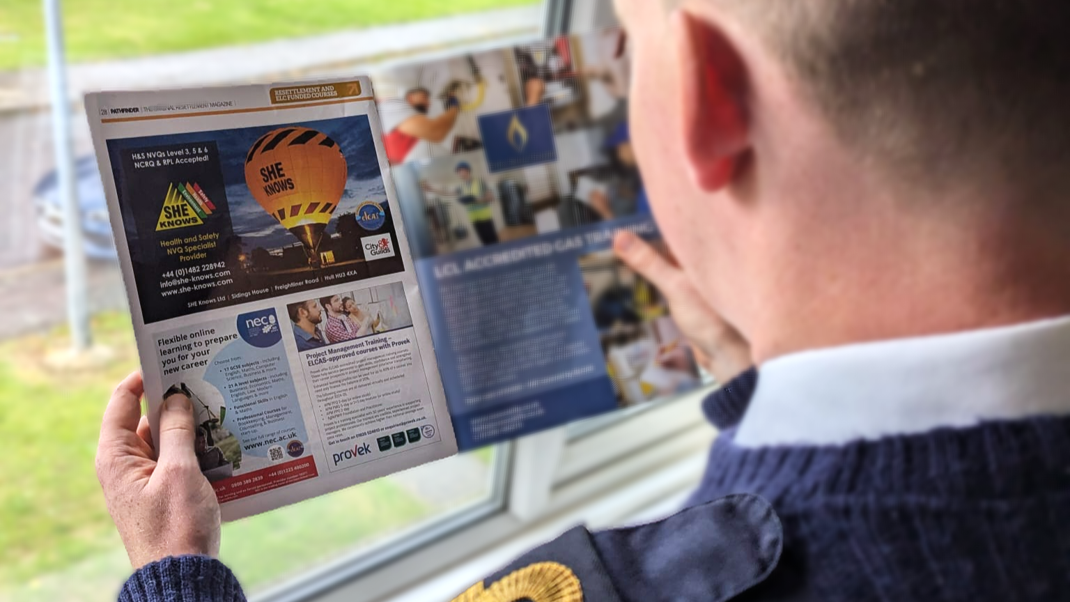 A person in a blue sweater reads a magazine, focusing on a page featuring an advertisement for hot air balloon rides and considering the Health & Safety measures involved.