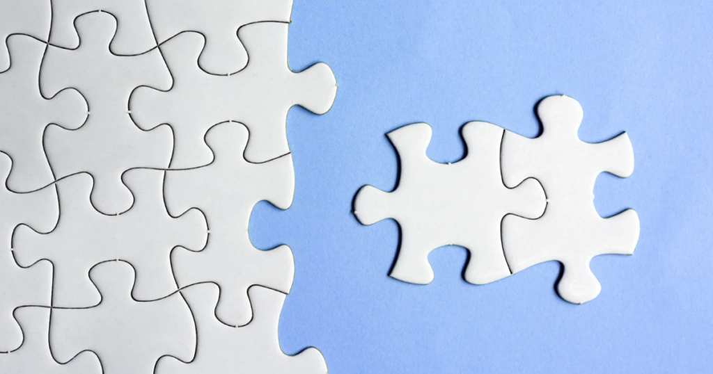 Incomplete white puzzle on a blue background with two missing pieces placed nearby.