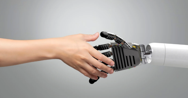 A human hand and a robotic hand reach towards each other, symbolizing innovation in the workplace, set against a plain gray background.