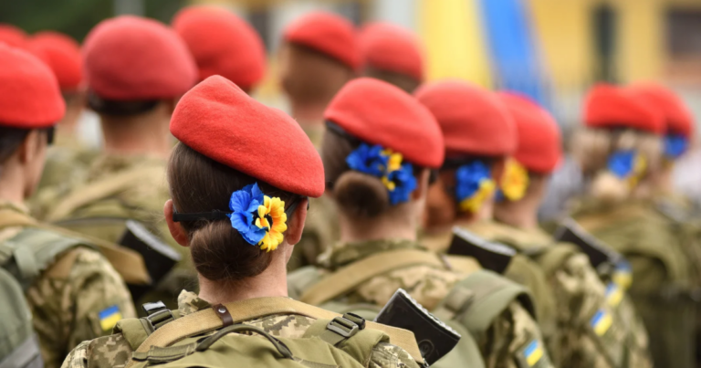 Soldiers in uniform from the Coalition of the Willing wear red berets and backpacks, with flowers in their hair.