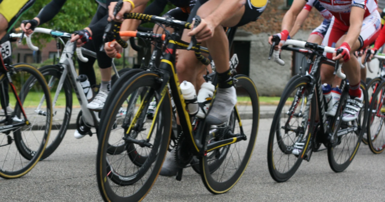 Cyclists in motion on a road during the 2025 RAFA Rides race, wearing helmets and cycling gear.