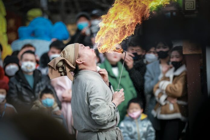 Fire performer entertains a crowd with fiery spectacle, capturing live audience reactions.