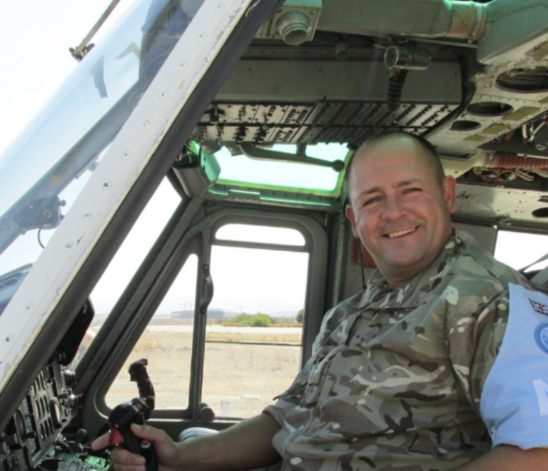 A person in camouflage military uniform sits in the cockpit of a helicopter, smiling at the camera—perhaps embracing a second career and finding purpose beyond probation.