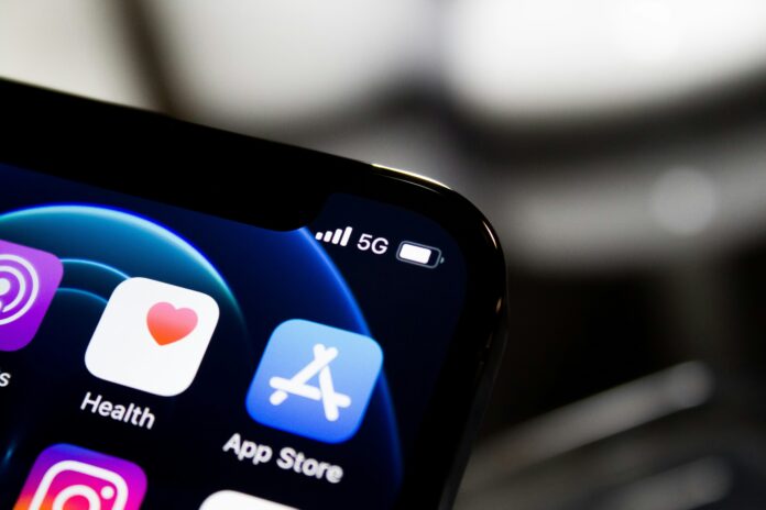 Close-up of a smartphone screen showing Health and App Store icons, emphasising a digital-first experience, with 5G signal and battery indicator visible at the top right.