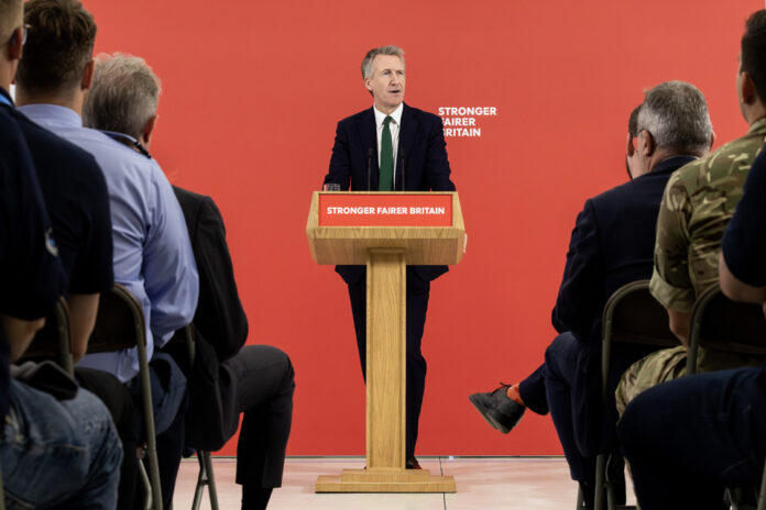 A man in a suit speaks at a lectern labelled 
